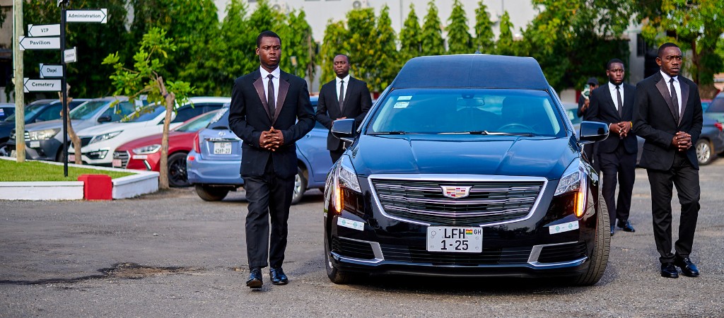 FamilyCare attendants standing with a hearse at a funeral procession